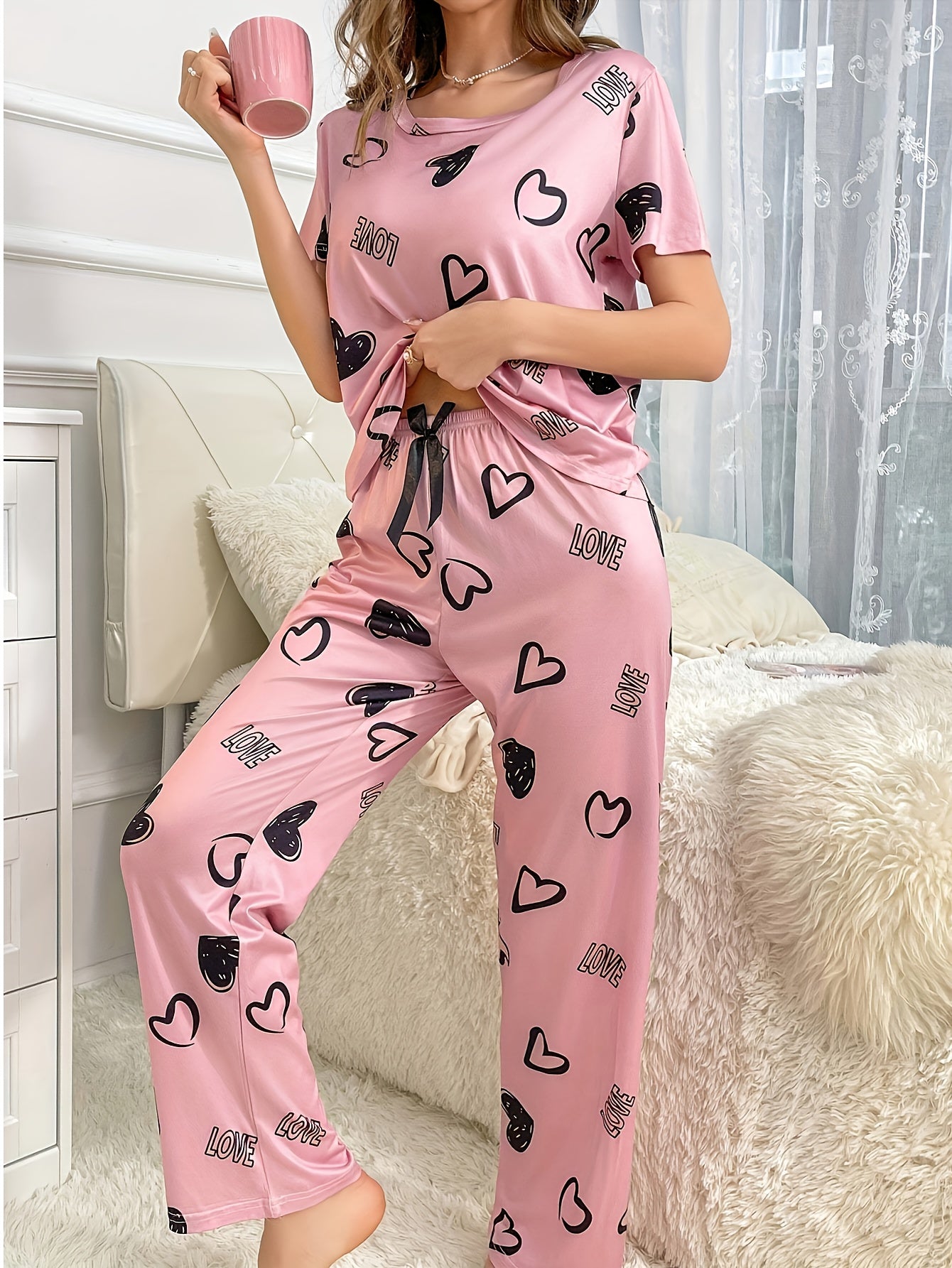 An adorable pink heart and letter print Women's pajama set, featuring a short-sleeve round-neck top paired with long pants, soft and comfortable